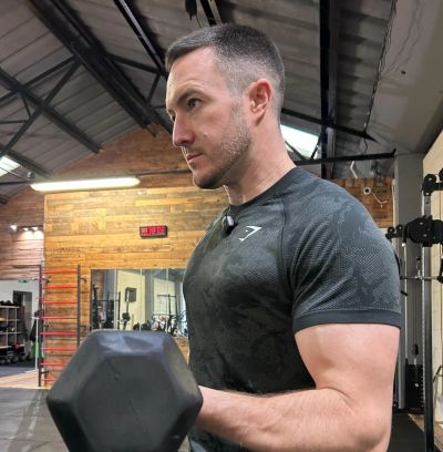 Man lifting a dumbbell in a gym.