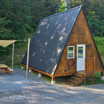 Cozy A-frame cabin with wooden exterior in a forest setting.