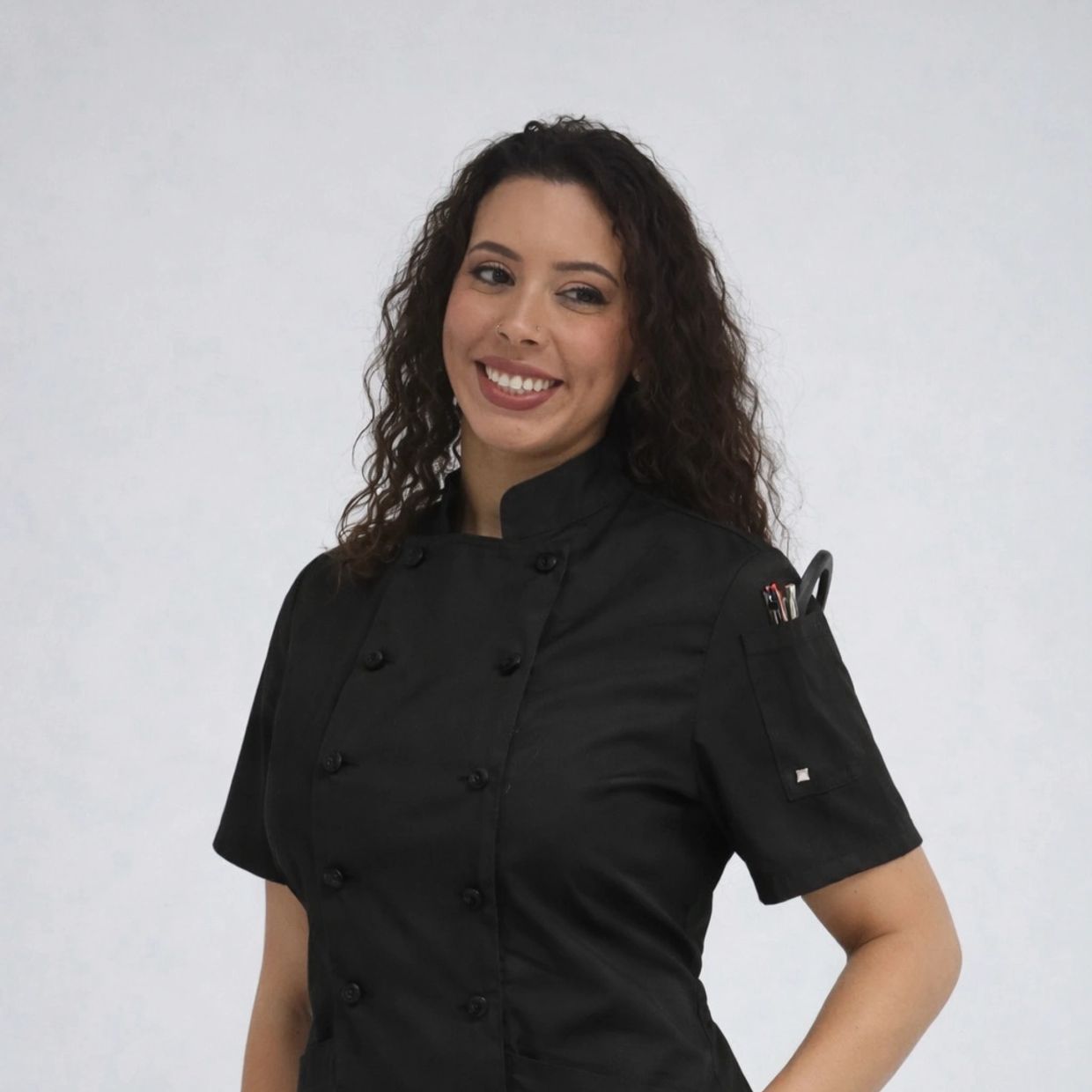 Smiling woman in a black chef coat against a plain background.