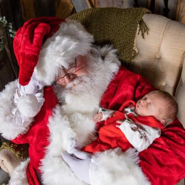 Santa Claus holding a sleeping baby.