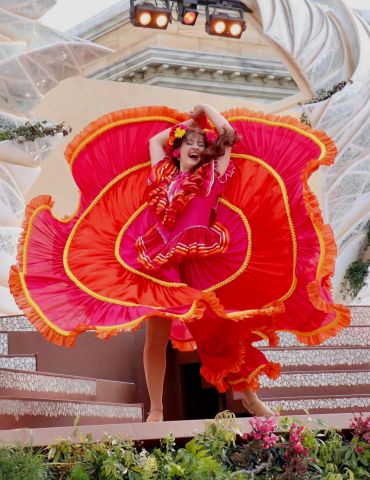 Woman dancing in vibrant red and orange dress.