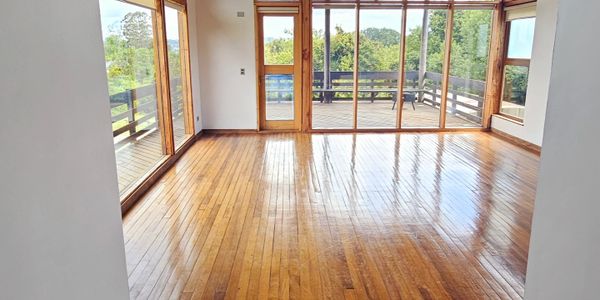 Empty room with polished wooden floors and large glass doors leading to a balcony.