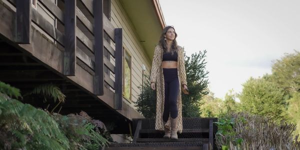 Woman in a long coat walking down outdoor stairs near a house.