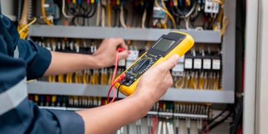 Electrician using a digital multimeter to test electrical circuits.