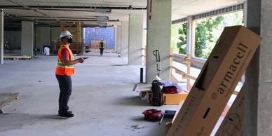 Construction worker in safety gear inspecting an unfinished building.