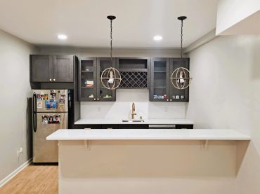 Modern kitchen with dark cabinets and white countertops by REM-CON Remodeling.