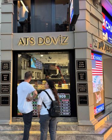 İki kişi döviz bürosu önünde konuşuyor.
