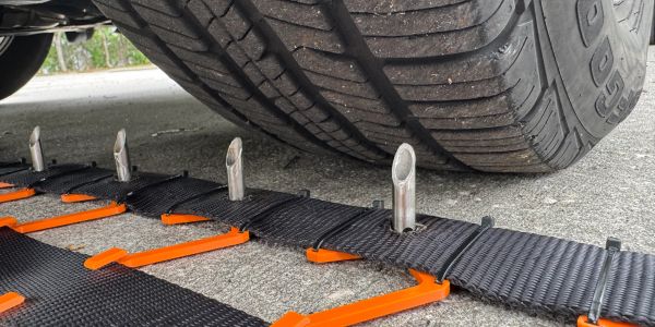 Vehicle tire on anti-skid mat with metal spikes.