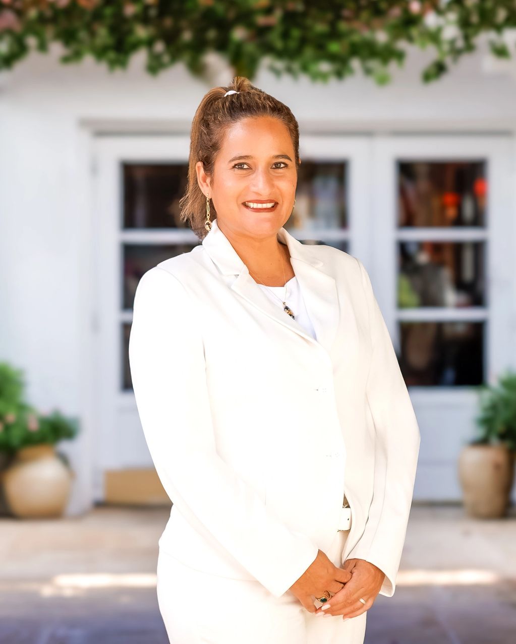 Woman in white suit smiling outdoors.