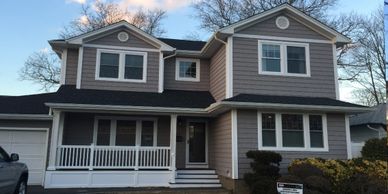 Two story beige house with white windows and porch on sunny day