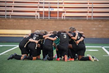 Soccer team huddling together on the field before the game.