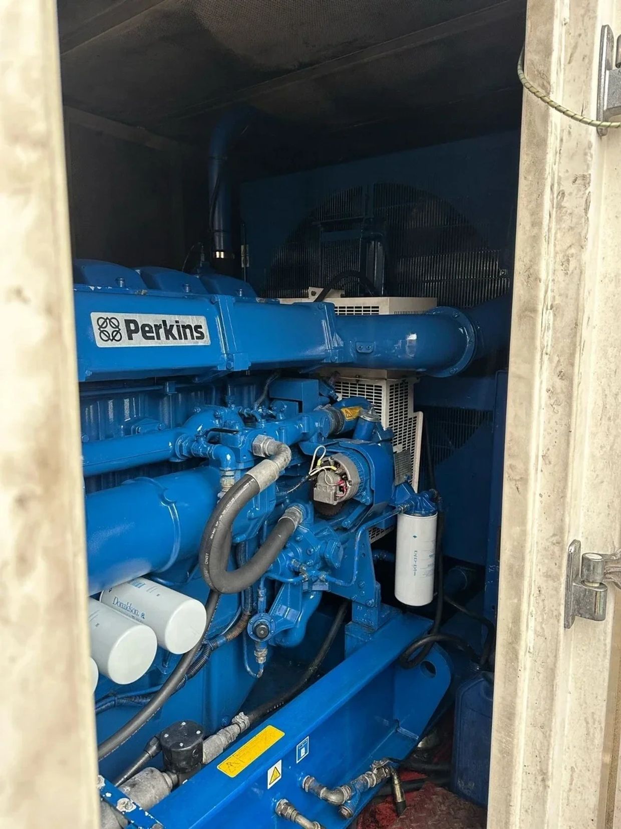Blue Perkins industrial engine inside a metallic enclosure.