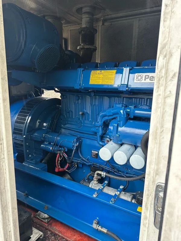 Blue industrial generator inside a metallic enclosure.