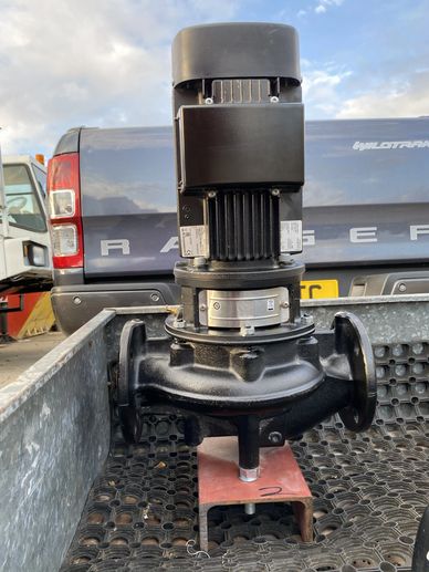 Industrial black electric motor pump placed on a metal surface outdoors.
