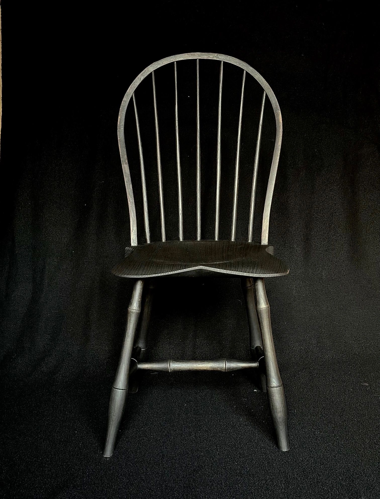 Chaise en bois noire sur fond noir.