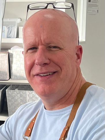 A person is painting a colorful mural on a large wall outdoors.