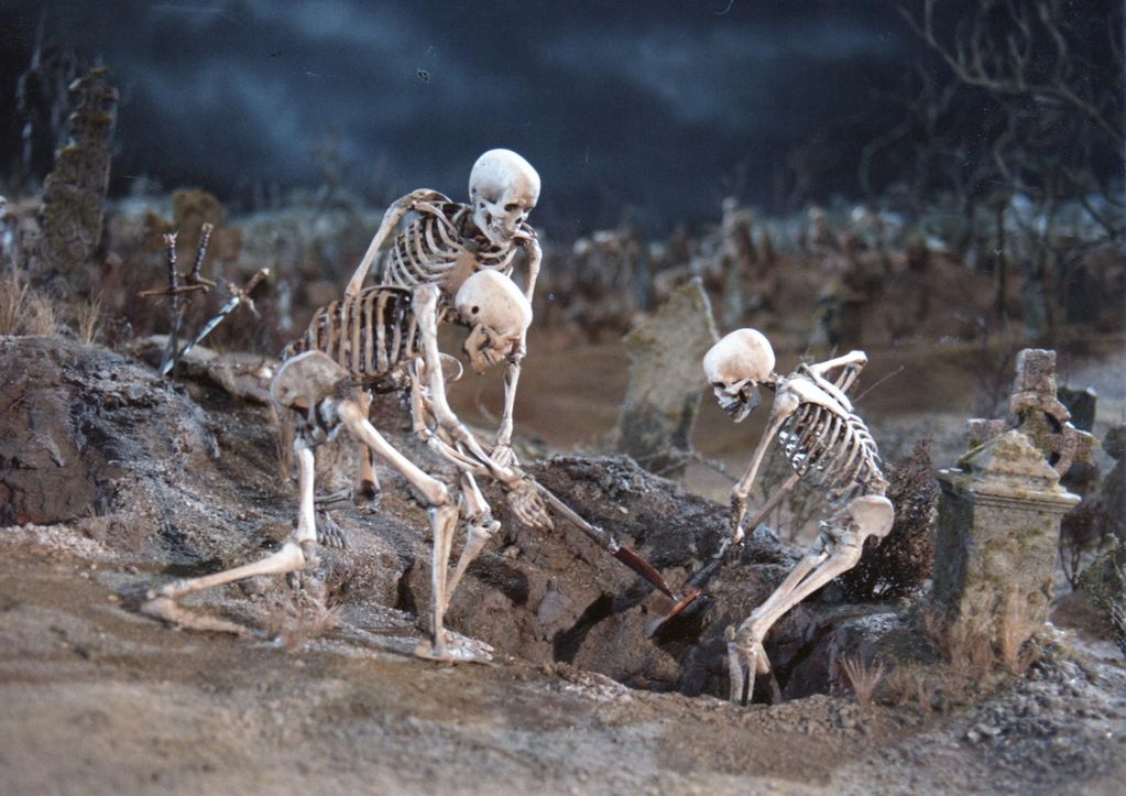 Image shows a miniature with three skeletons digging up a grave.  There are tombstones, dead looking