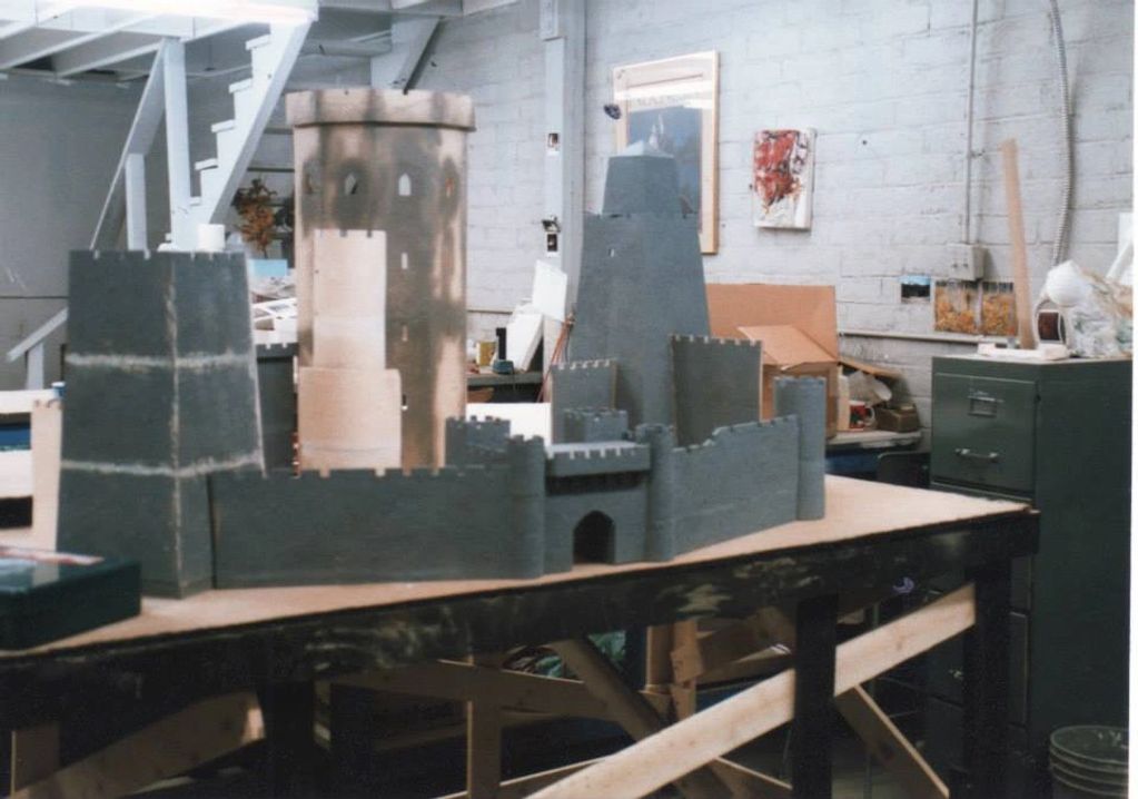 Image shows partially constructed castle model on a bench.  The castle is shades of grey and white.