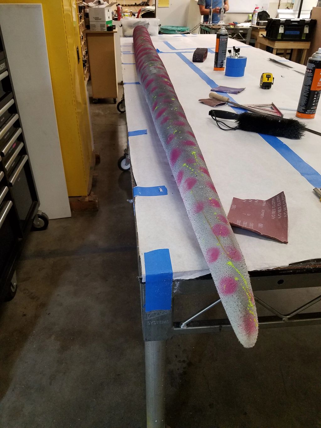 Image of purple and grey tentacle on a white paper covered table.