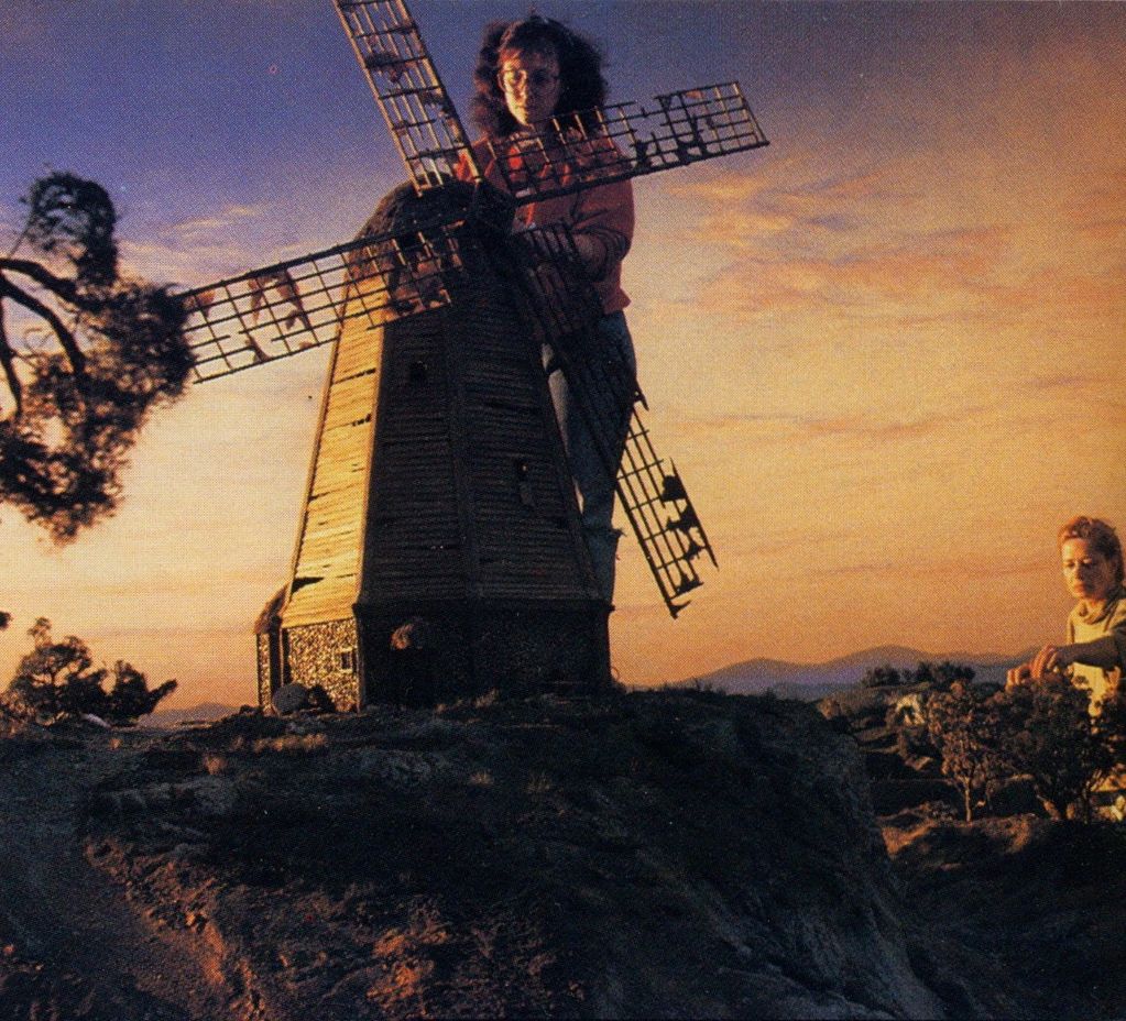 Image shows a miniature windmill on a set.  Two women are working on the set, one behind the mill an