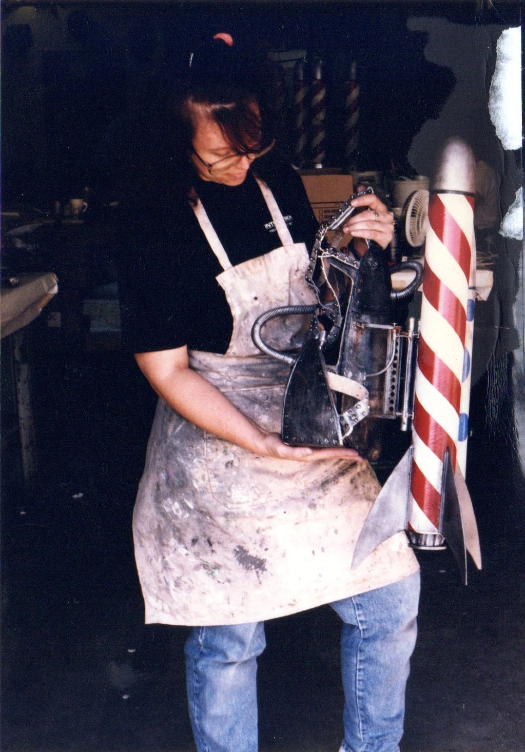 Image shows a woman holding a rocket pack harness with rockets attached.
