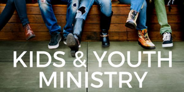Feet of young people above Kids & Youth Ministry sign.