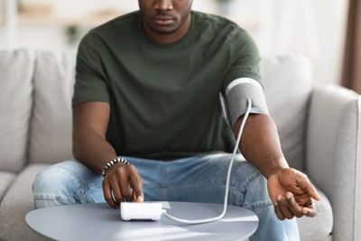 black man measuring blood pressure at home