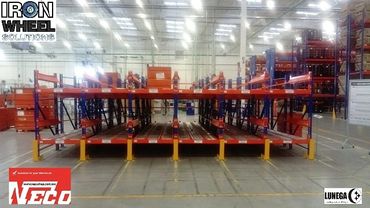 Industrial metal shelving system in a warehouse setting with safety barriers.
