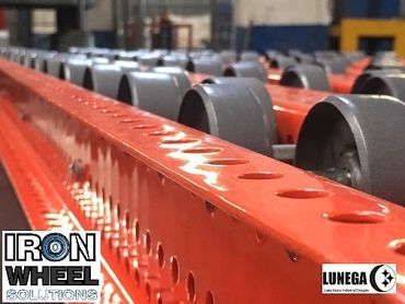 Close-up of red industrial conveyor rollers with logos of Iron Wheel Solutions and LUNega.