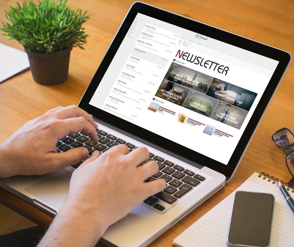 Hands typing human-led content on a laptop showing a digital newsletter email on screen.