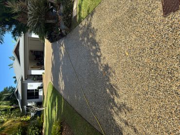 A modern house with an open garage and a long pebble driveway.