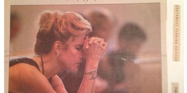 A woman with short hair and a bracelet is deep in thought or prayer.