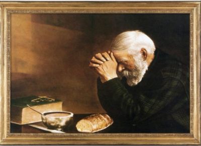 Elderly man praying before a meal.