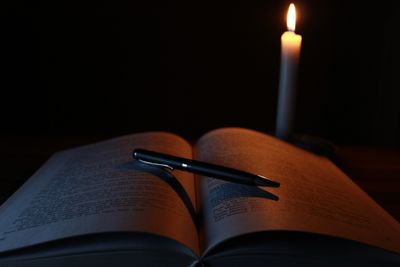 A candle-lit book and pen.