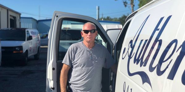Kenneth Quattlander standing and posing in front of his work van. Owner of Authentic Air and Heat
