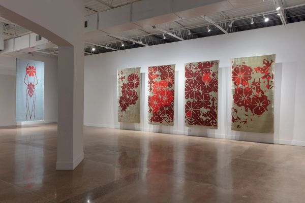 Contemporary art gallery with large red floral paintings on white walls and polished floors.