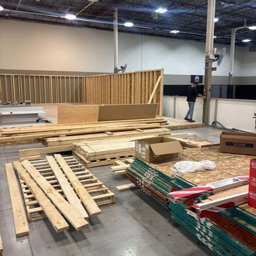 Indoor construction site with wooden materials and a worker.