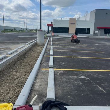 Newly paved parking lot with fresh curbs and empty spaces.