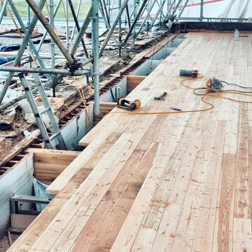 Wooden floorboards being installed with power tools on site.
