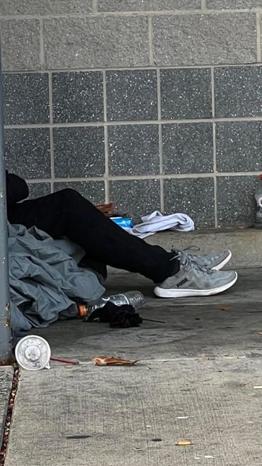 Person lying on the ground against a gray tiled wall.