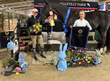 Two equestrians pose with a black horse and awards at Chantilly Farm.