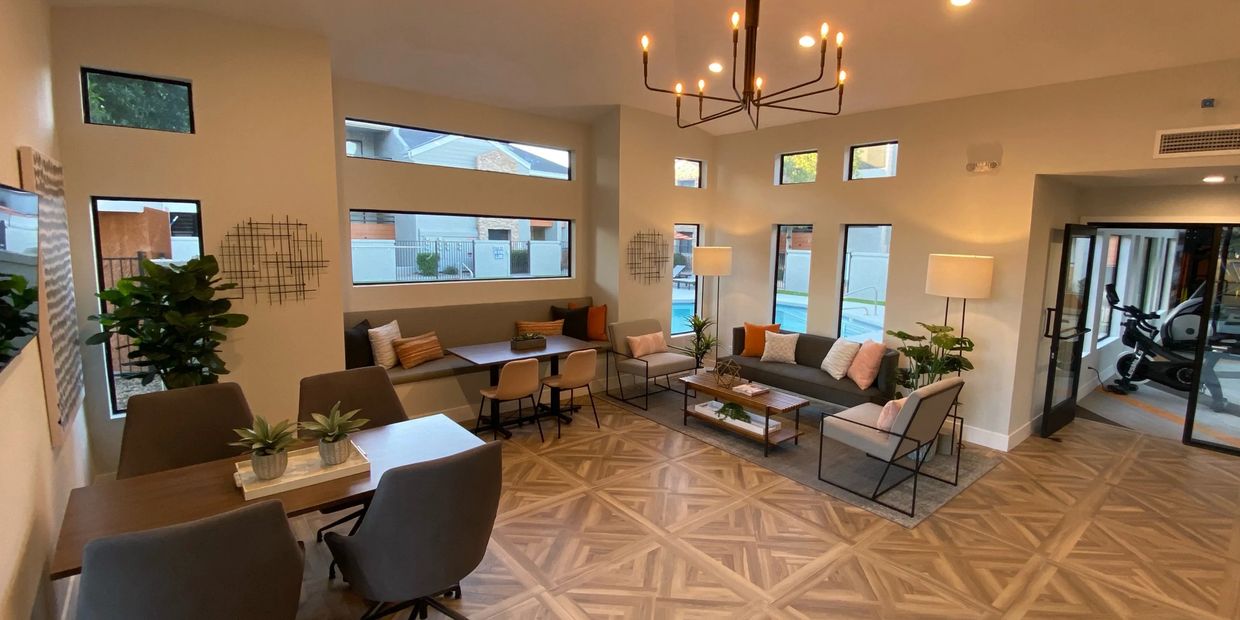 Modern living room with cozy seating, natural light, and access to a gym area.