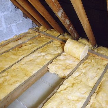 Rolls of Rockwool loft insulation being laid in a loft. Showing how it should be put to the eaves.