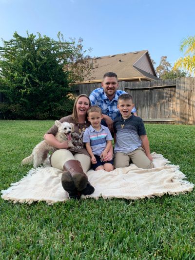Family of four with a dog posing on a blanket outdoors.