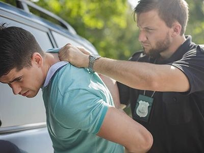 guy in green shirt being arrested by cop