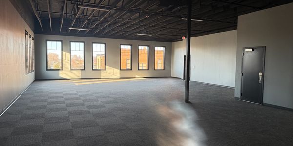 Empty office space with large windows and dark ceiling.