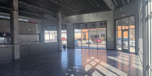 Spacious empty room with large windows and brick pillars.