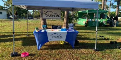 Outdoor event booth for SWCBC under a canopy with informational materials.
