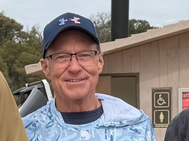 Smiling man wearing glasses and a cap.