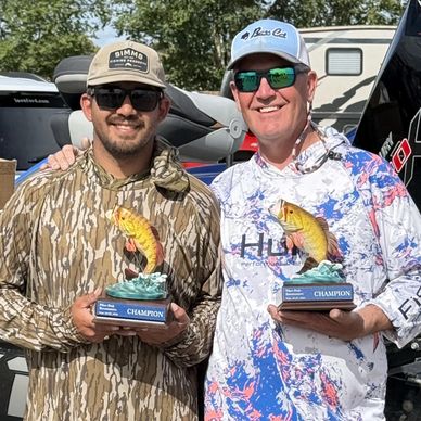 Two men holding fishing champion trophies.